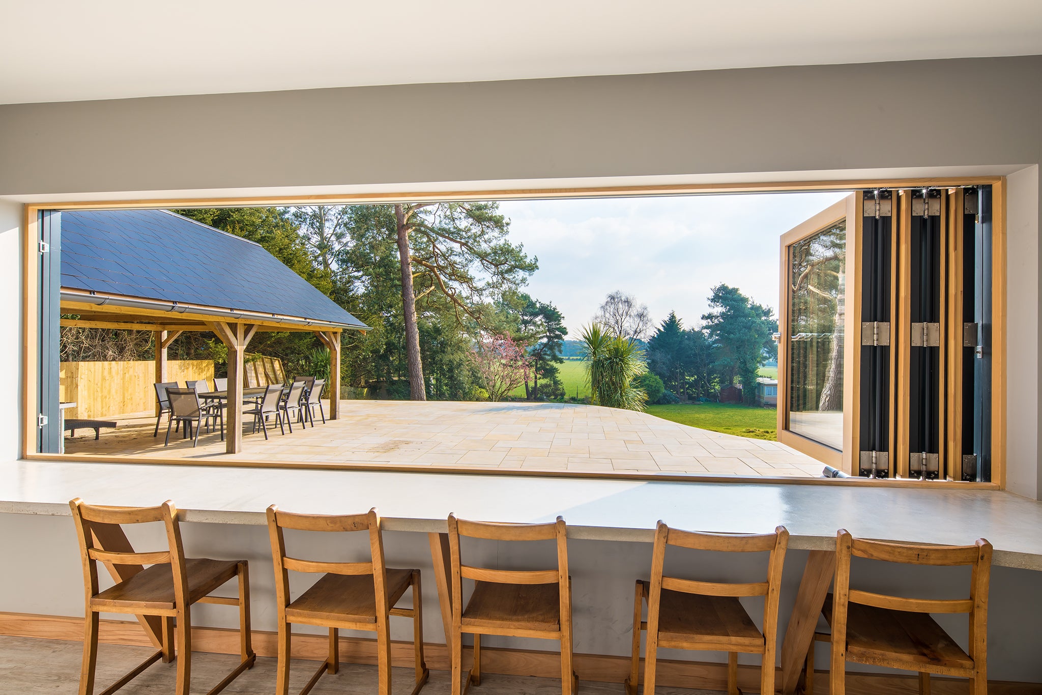 Internal side view of an open, triple-glazed, aluminum-clad bi-fold window in a Ringwood refurbishment.