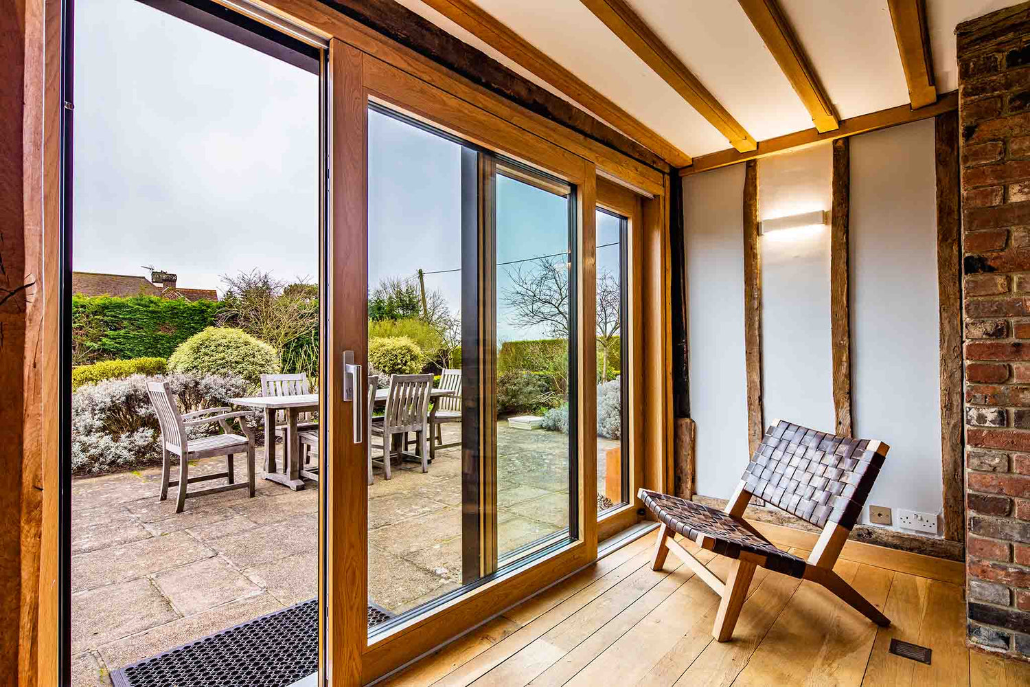 Modern room with large triple-glazed glass doors leading to a patio area with furniture.