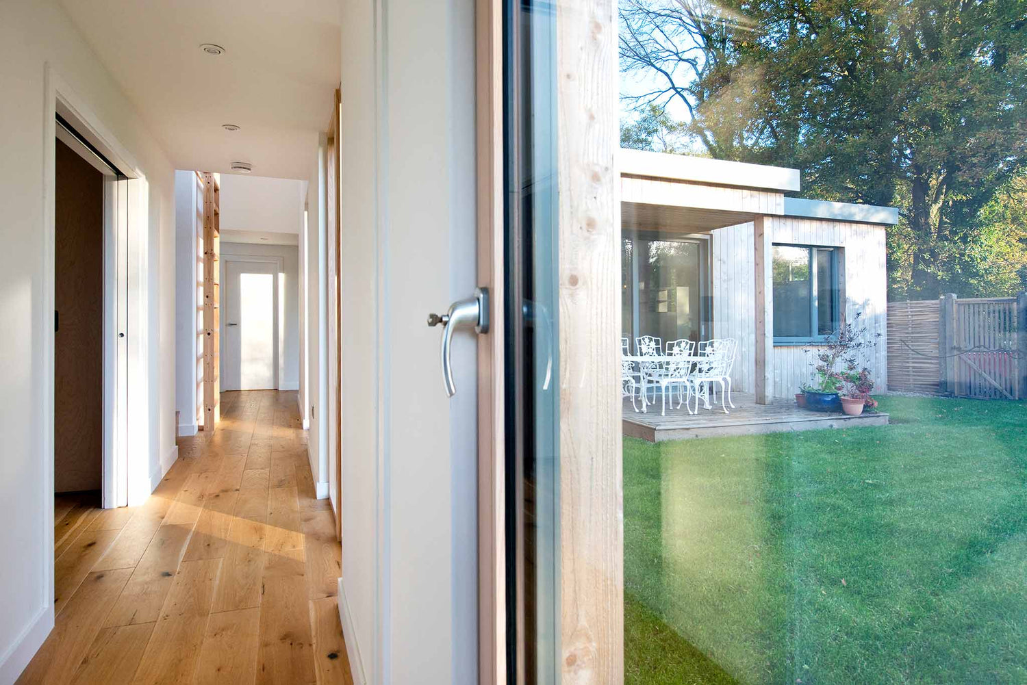 Modern house interior with a view of a garden through a triple-glazed glass door.