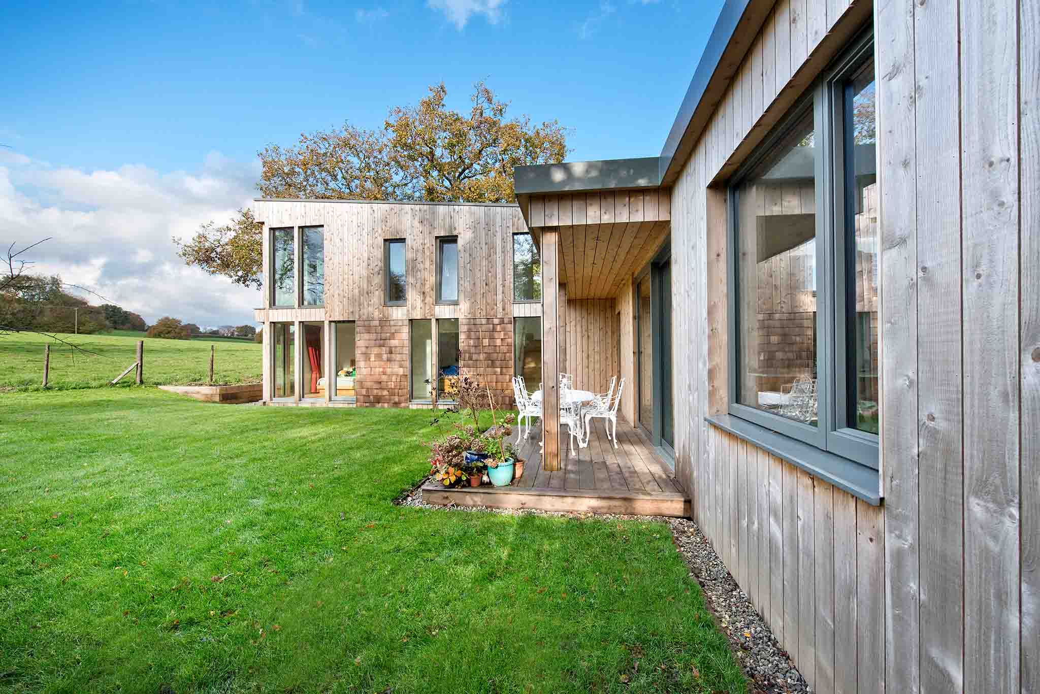 Modern triple-glazed house with wooden exterior and green lawn