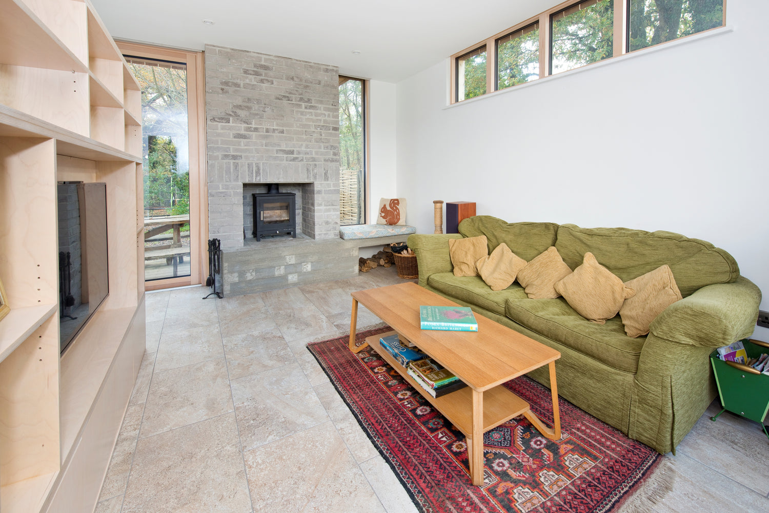 Triple glazed living room with green sofa, wooden coffee table, and stone fireplace.