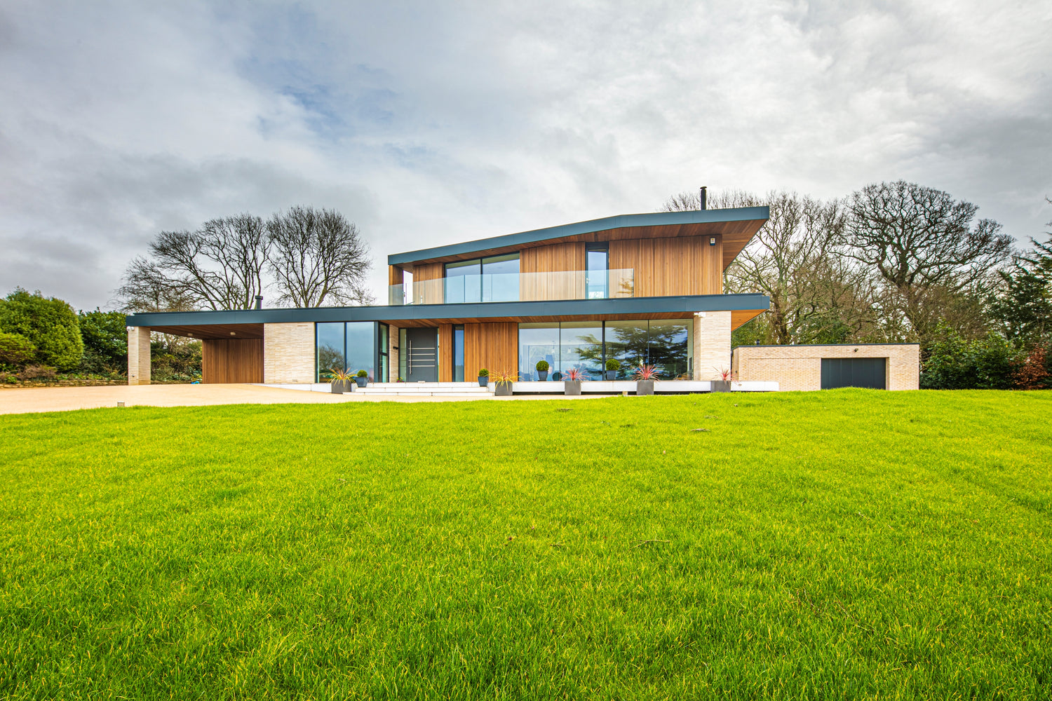 Modern triple-glazed house with a green lawn and trees in the background