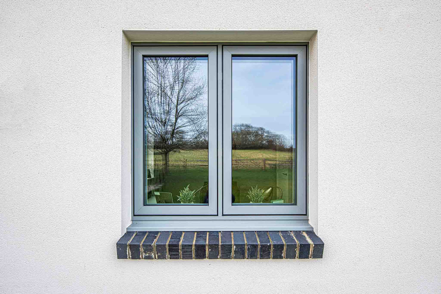 Triple-glazed window with a view of trees and sky on a white wall