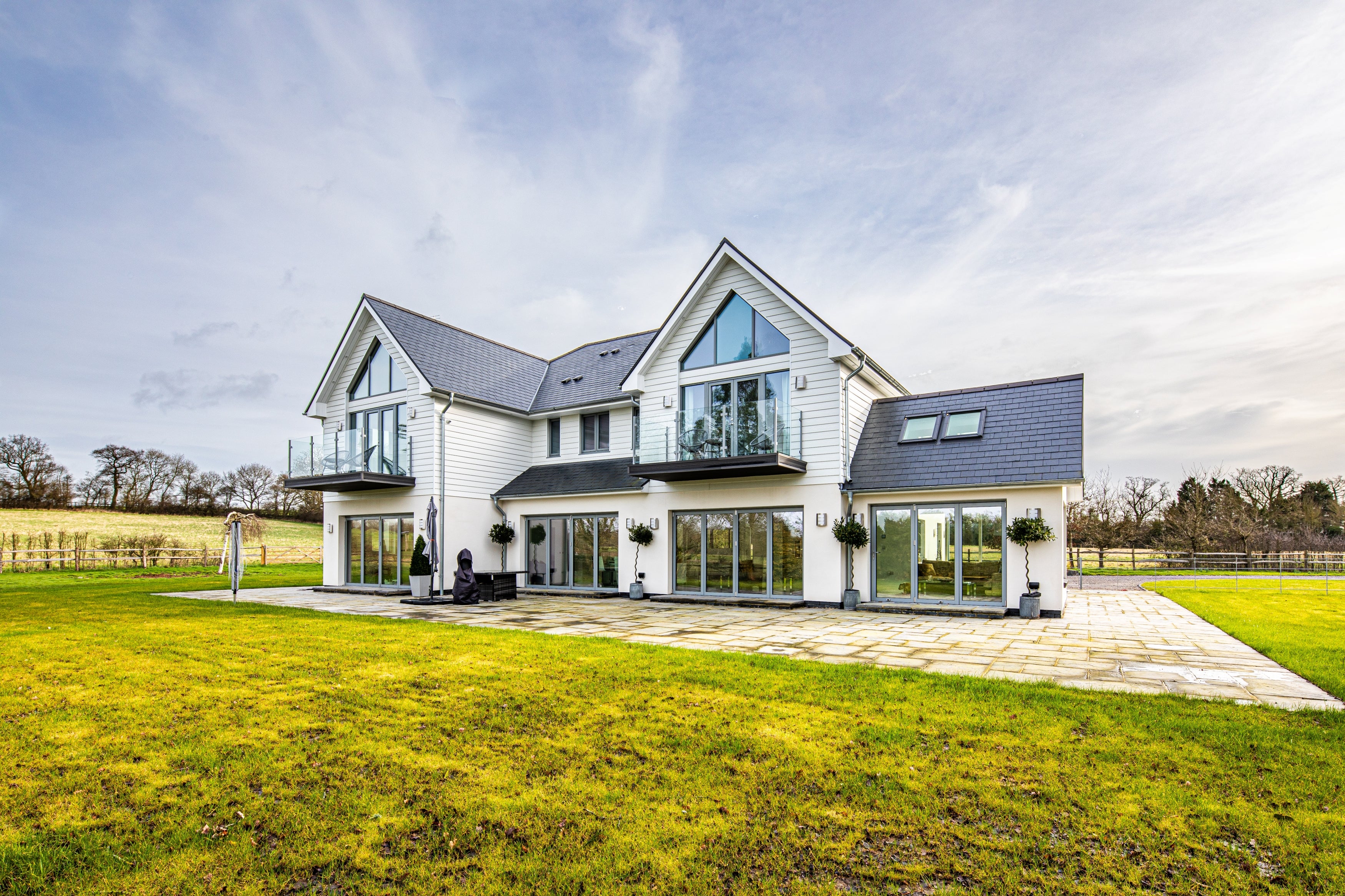 Modern house with triple glazed windows, grey roof and white walls in a rural setting