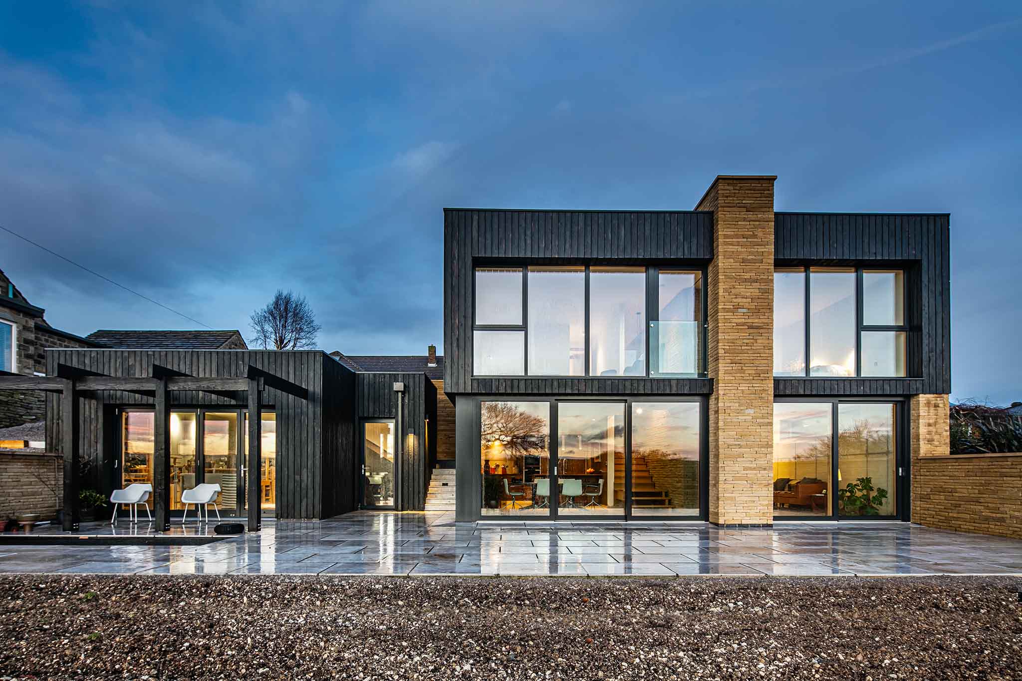 Modern house with large triple-glazed glass windows and a dark exterior design.