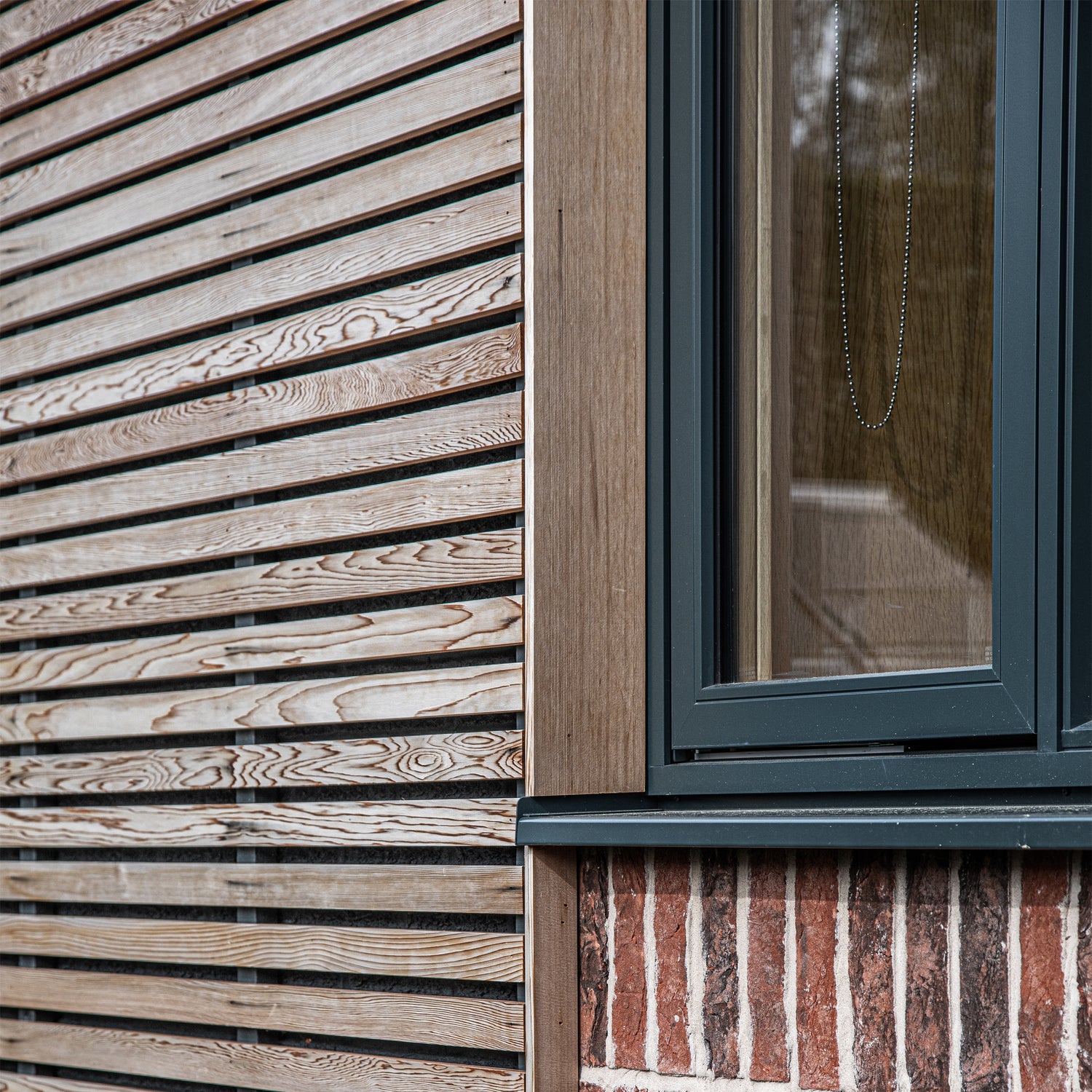 Close-up of a building exterior with wooden slat wall and triple-glazed window.