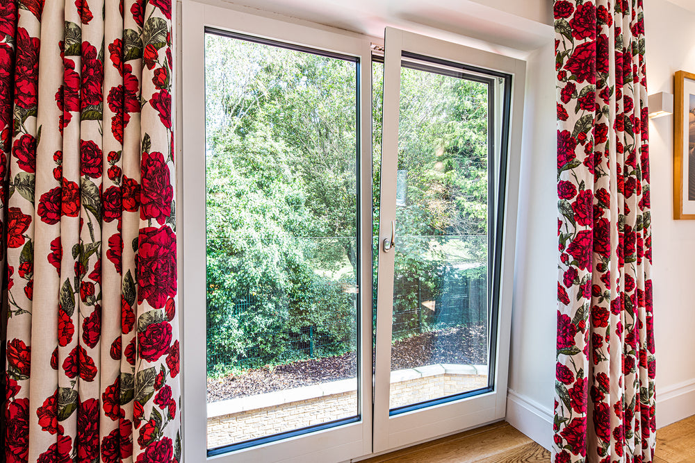 triple-glazed window with red floral curtains on a white wall