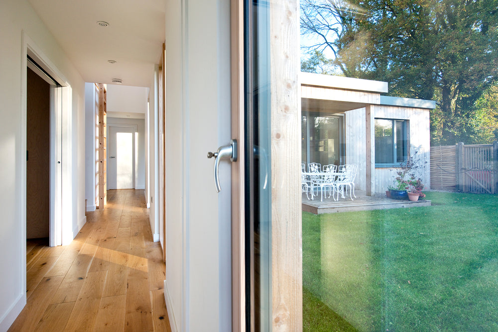 Modern house interior with a view of a garden through a triple-glazed glass door.