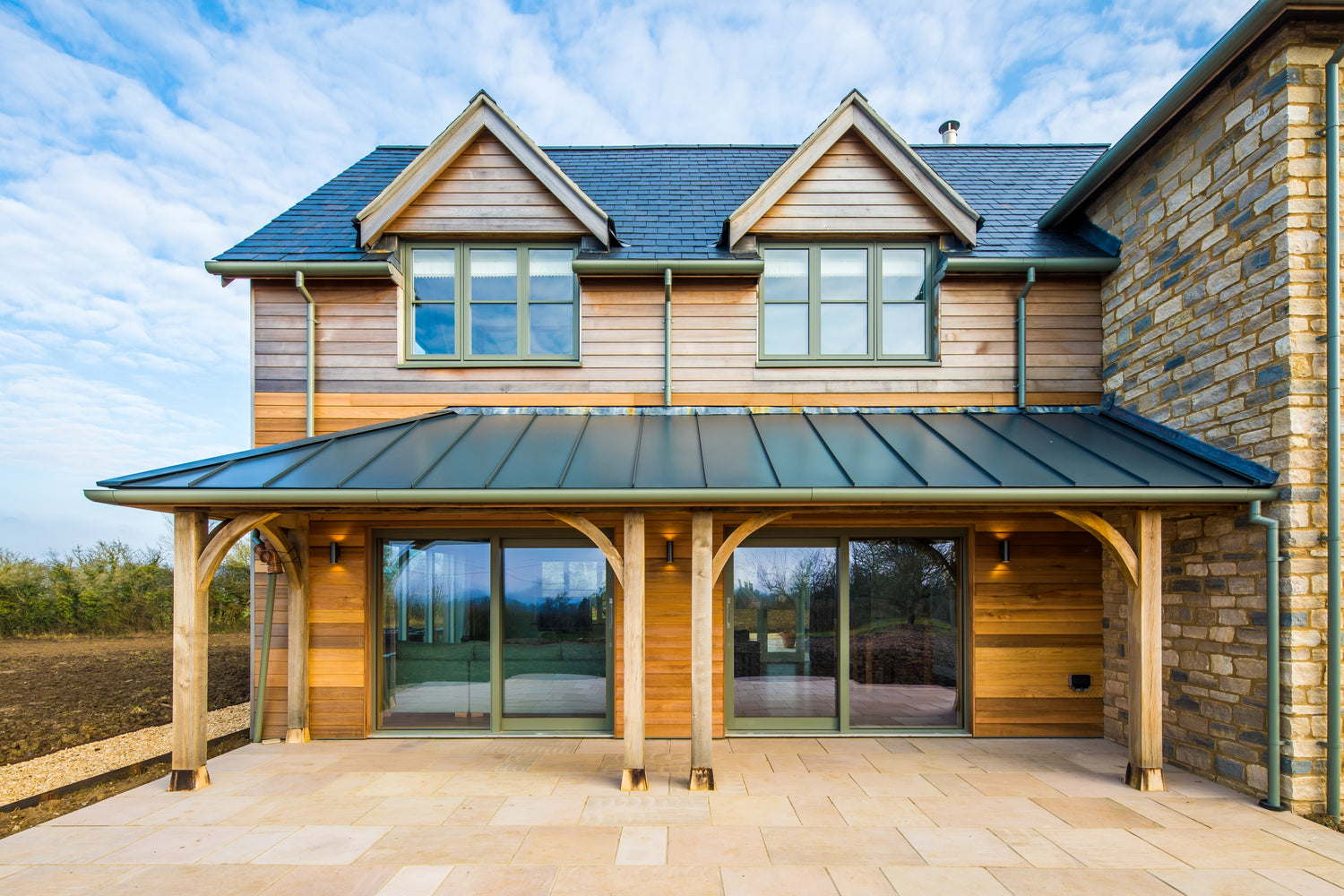 Modern house with wooden exterior and double-glazed glass doors, under a blue sky.