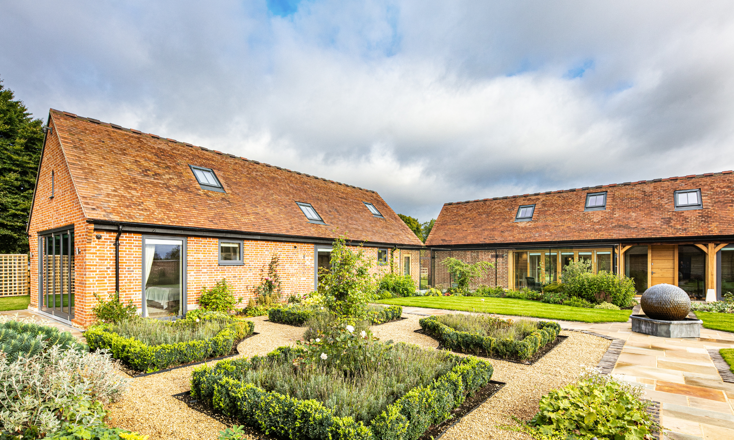 Modern house with triple-glazed windows, a garden and neatly trimmed hedges under a cloudy sky.