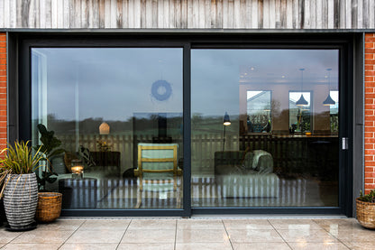 External view of a triple-glazed, aluminum-clad sliding door in an eco-style passive house.