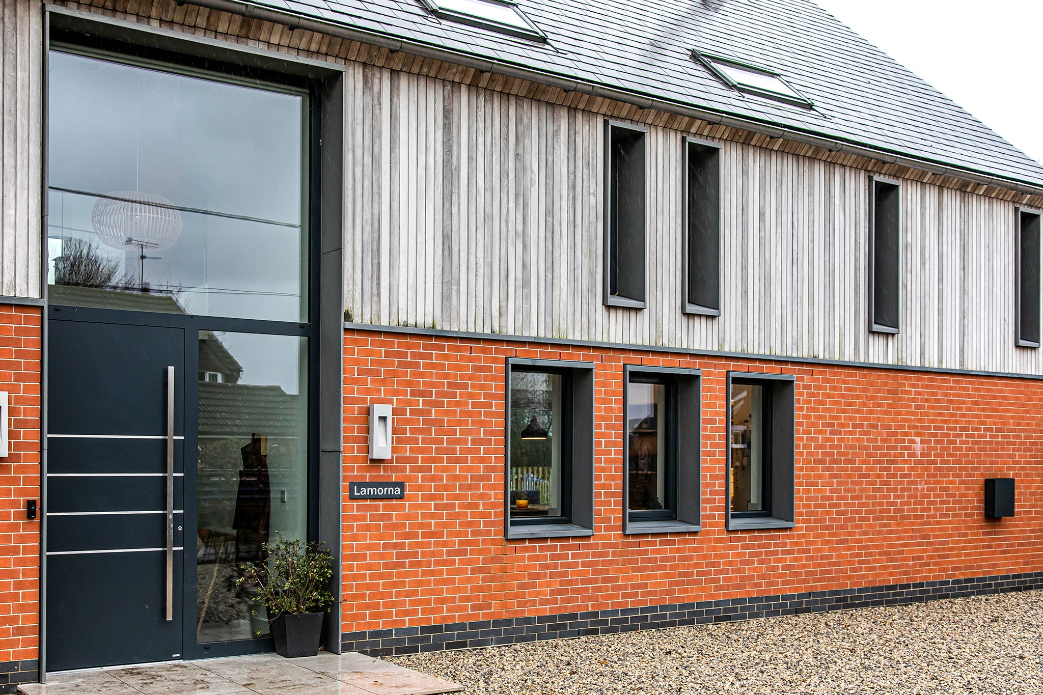 External view of a triple-glazed, aluminum-clad timber panel door in an eco-style passive house.