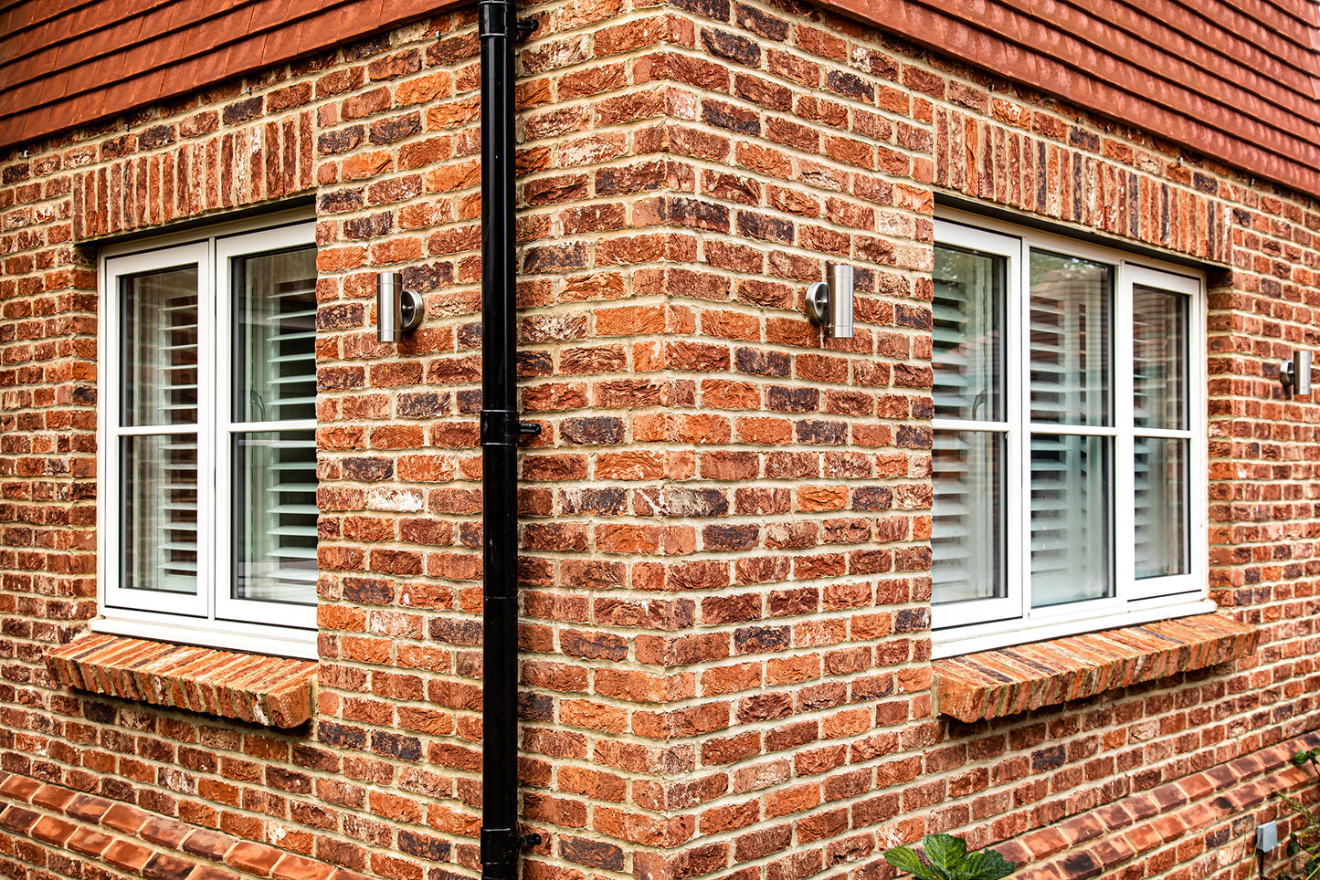 External corner view of a triple-glazed, aluminum-clad window in a traditional new build.