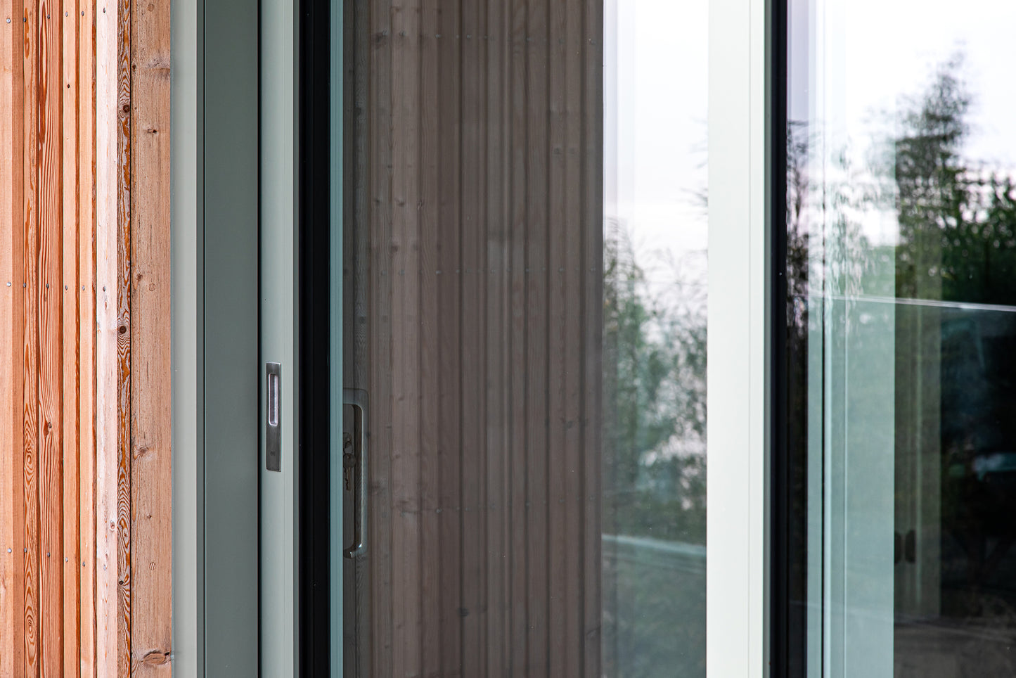 External detail view of a triple-glazed, aluminum-clad handle in a seaside passive home.