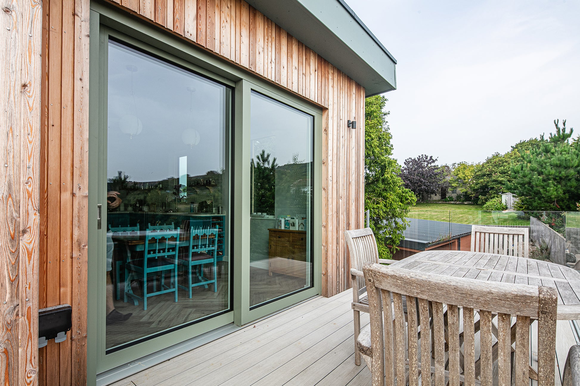 Balcony view of a triple-glazed, aluminum-clad sliding door in a seaside passive home.