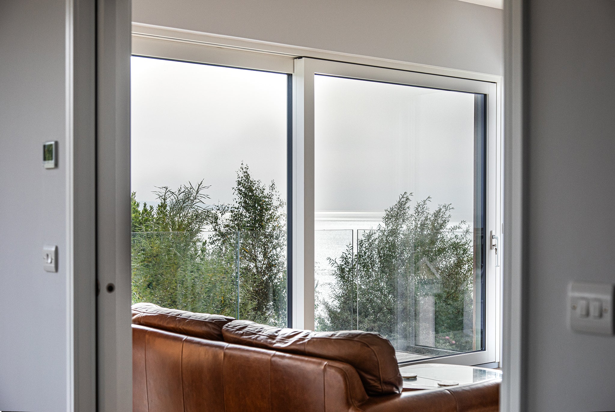 Internal view of a closed, triple-glazed sliding door in a seaside passive home.