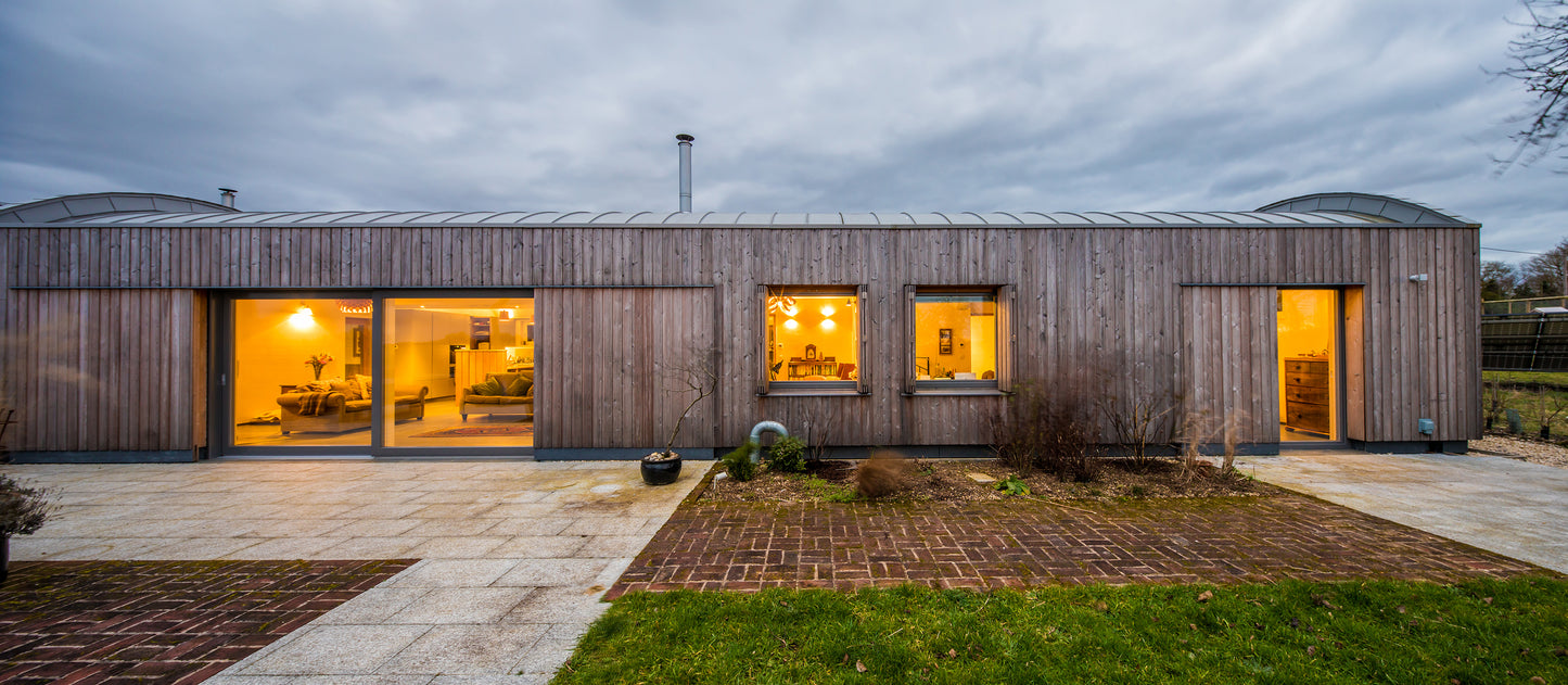 External side view of a triple-glazed, aluminum-clad feature in a barn-style low-energy home.