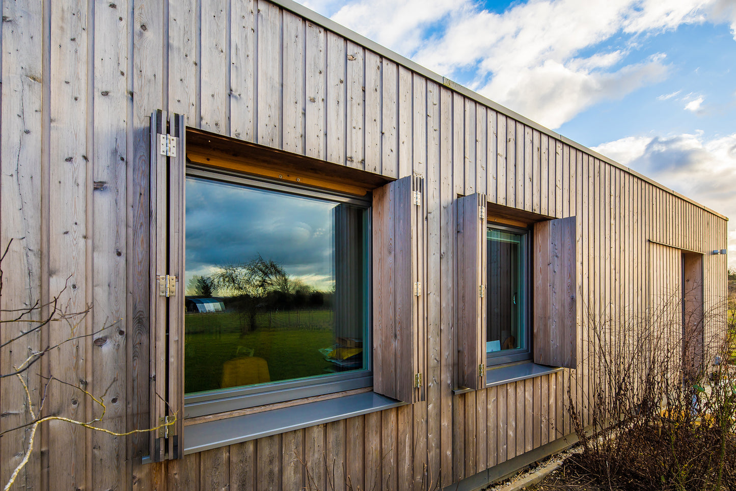 External side view of a triple-glazed, aluminum-clad window in a barn-style low-energy home.