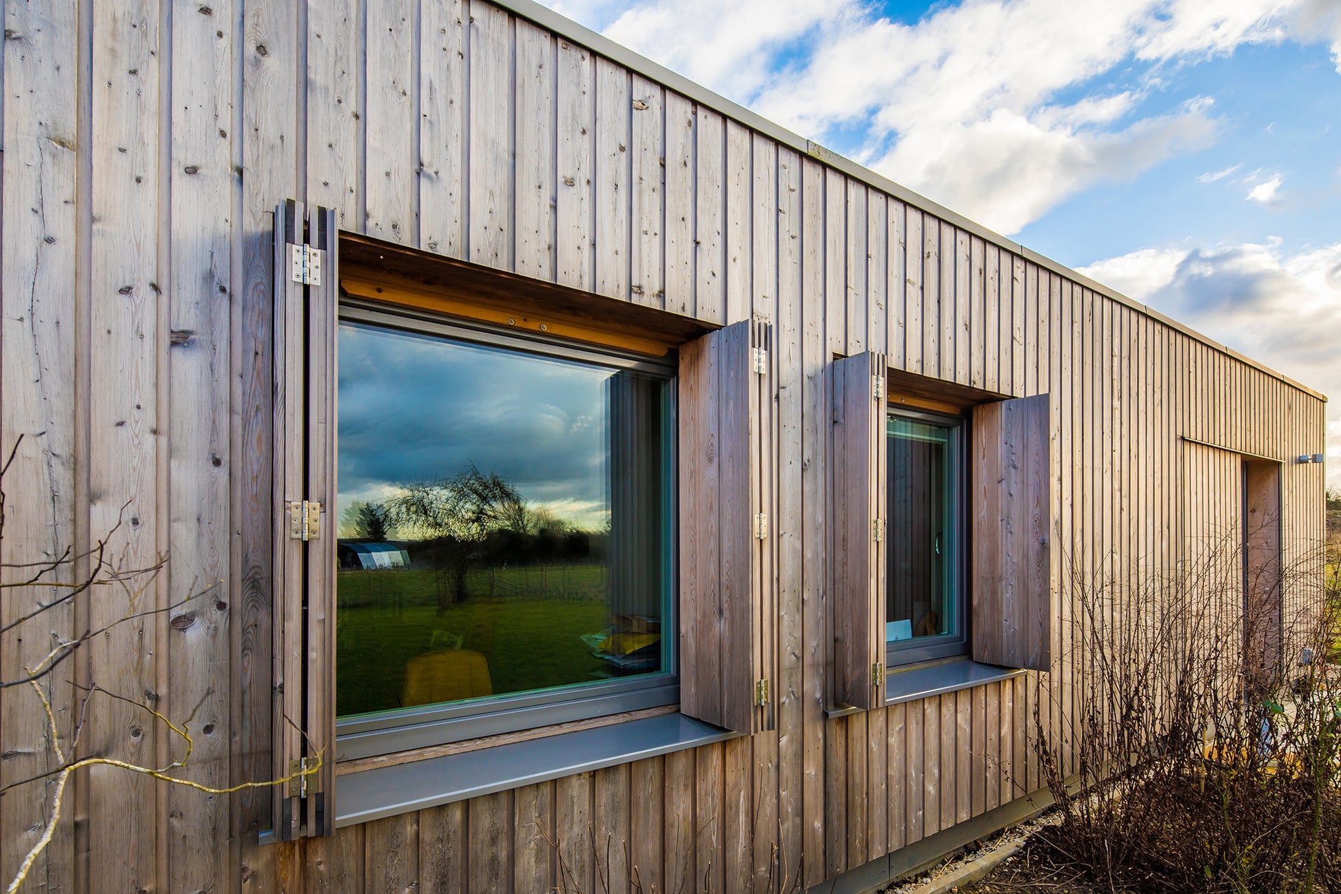 External side view of a triple-glazed, aluminum-clad window in a barn-style low-energy home.