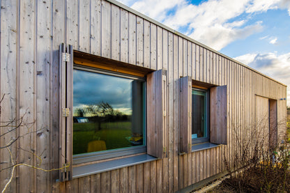 External side view of a triple-glazed, aluminum-clad window in a barn-style low-energy home.