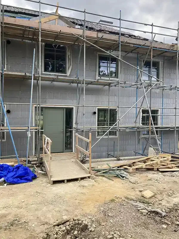 House under construction with triple-glazed windows, scaffolding and a ramp