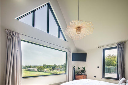 Modern bedroom with large triple-glazed windows, ceiling light fixture, and curtains.