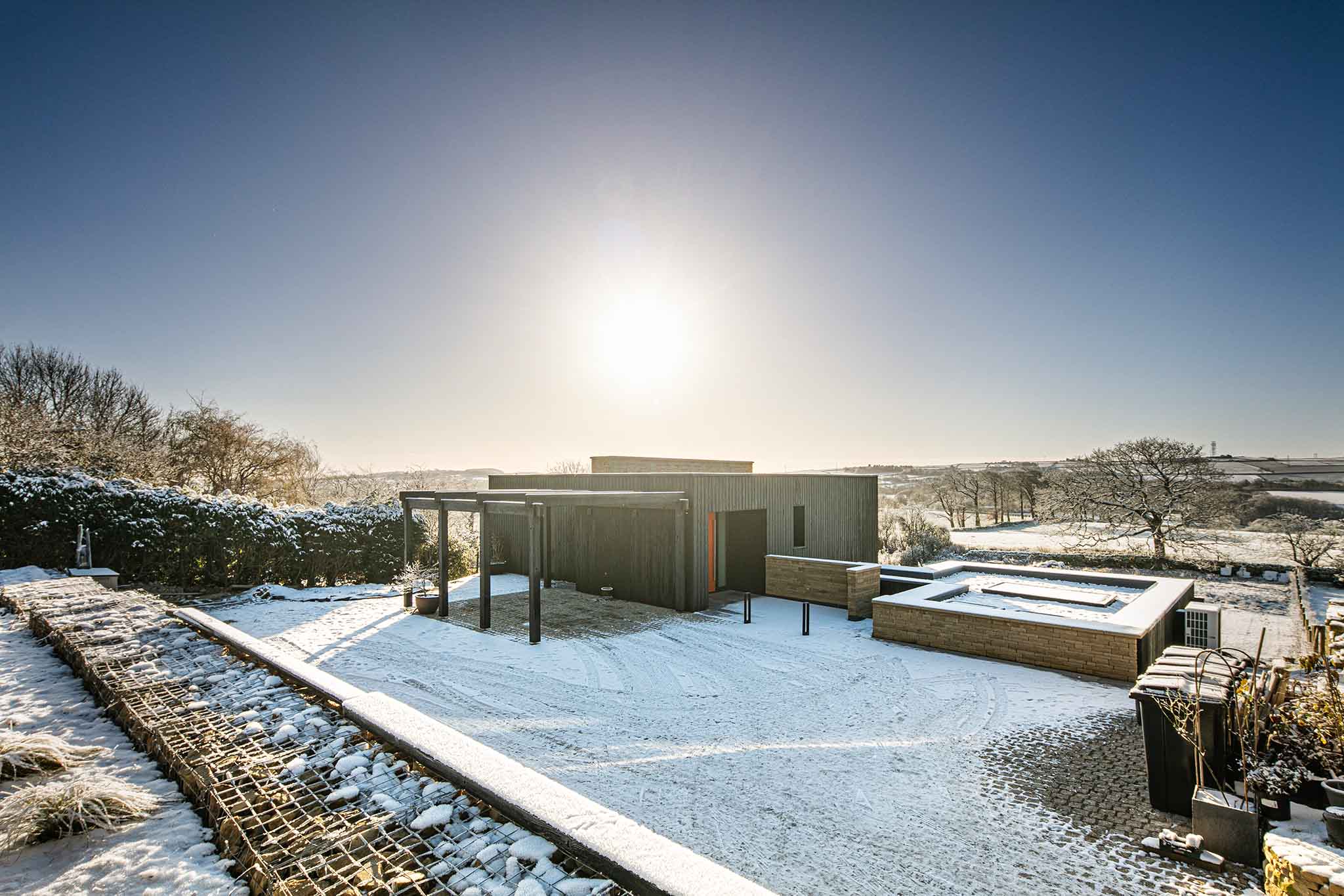 Modern house with triple-glazed windows, a snowy landscape and clear blue sky