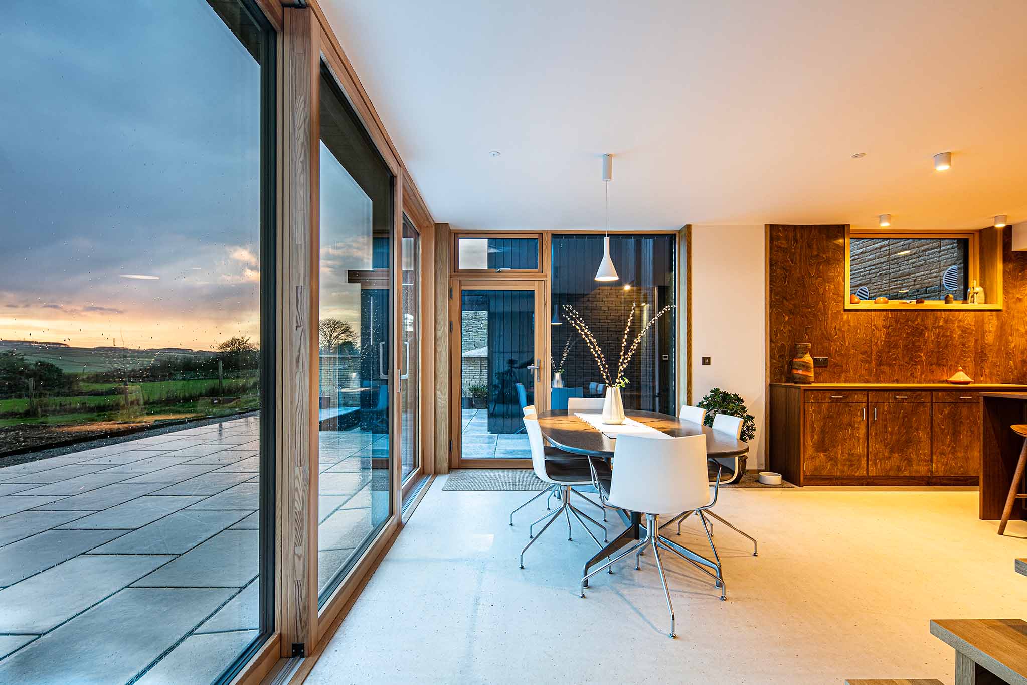 Modern dining area with large triple-glazed windows overlooking a scenic landscape