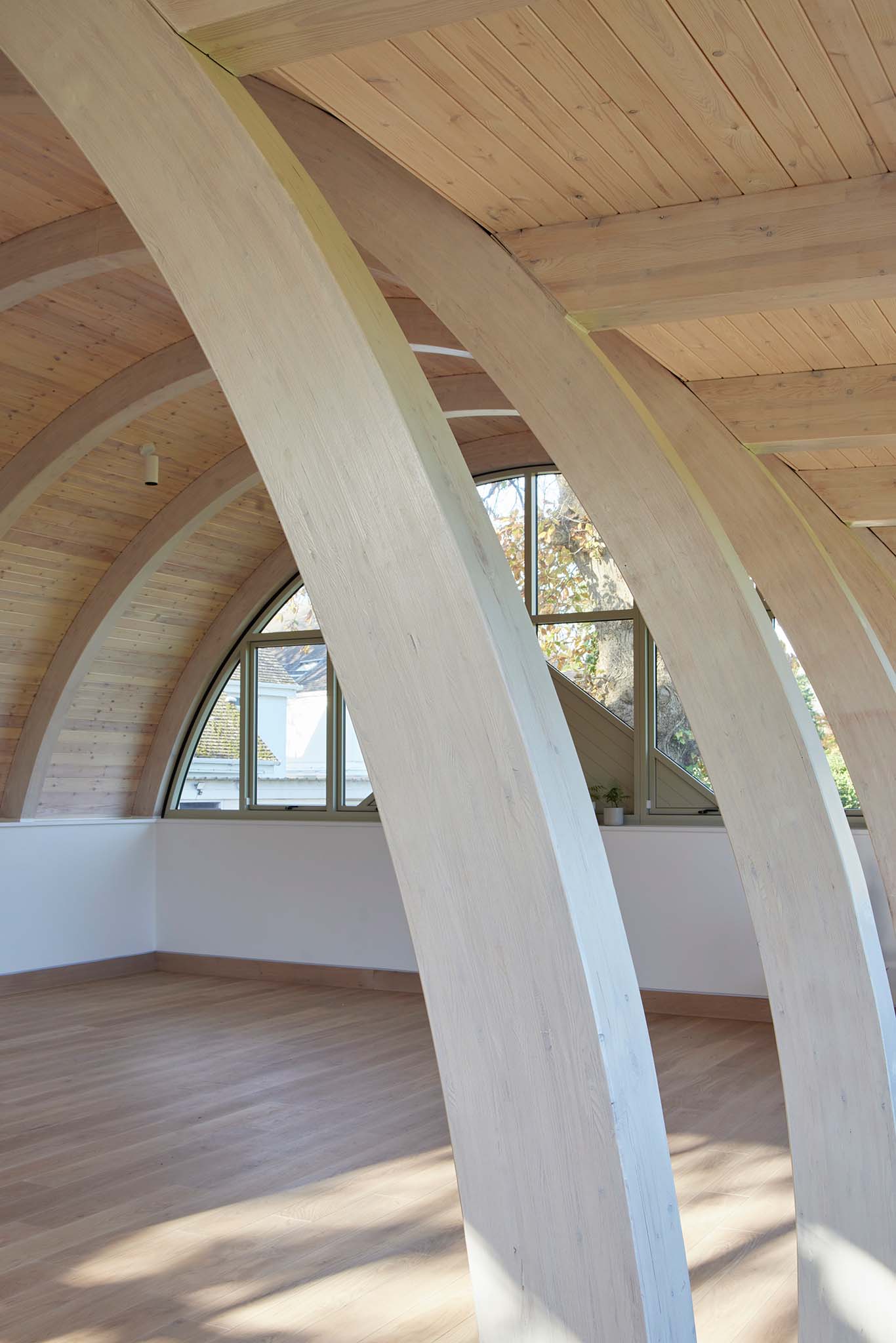 Wooden interior with curved beams and a triple-glazed window
