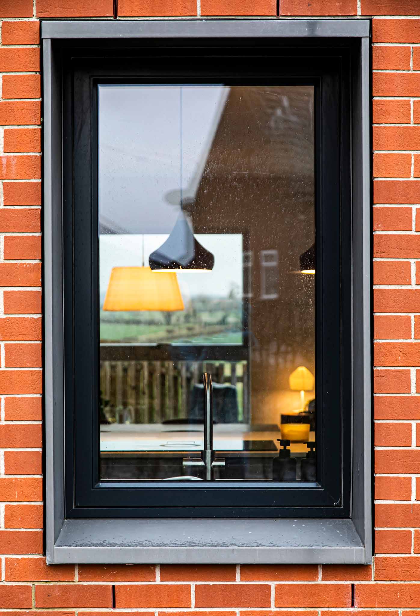 Triple-glazed window with black frame on a red brick wall