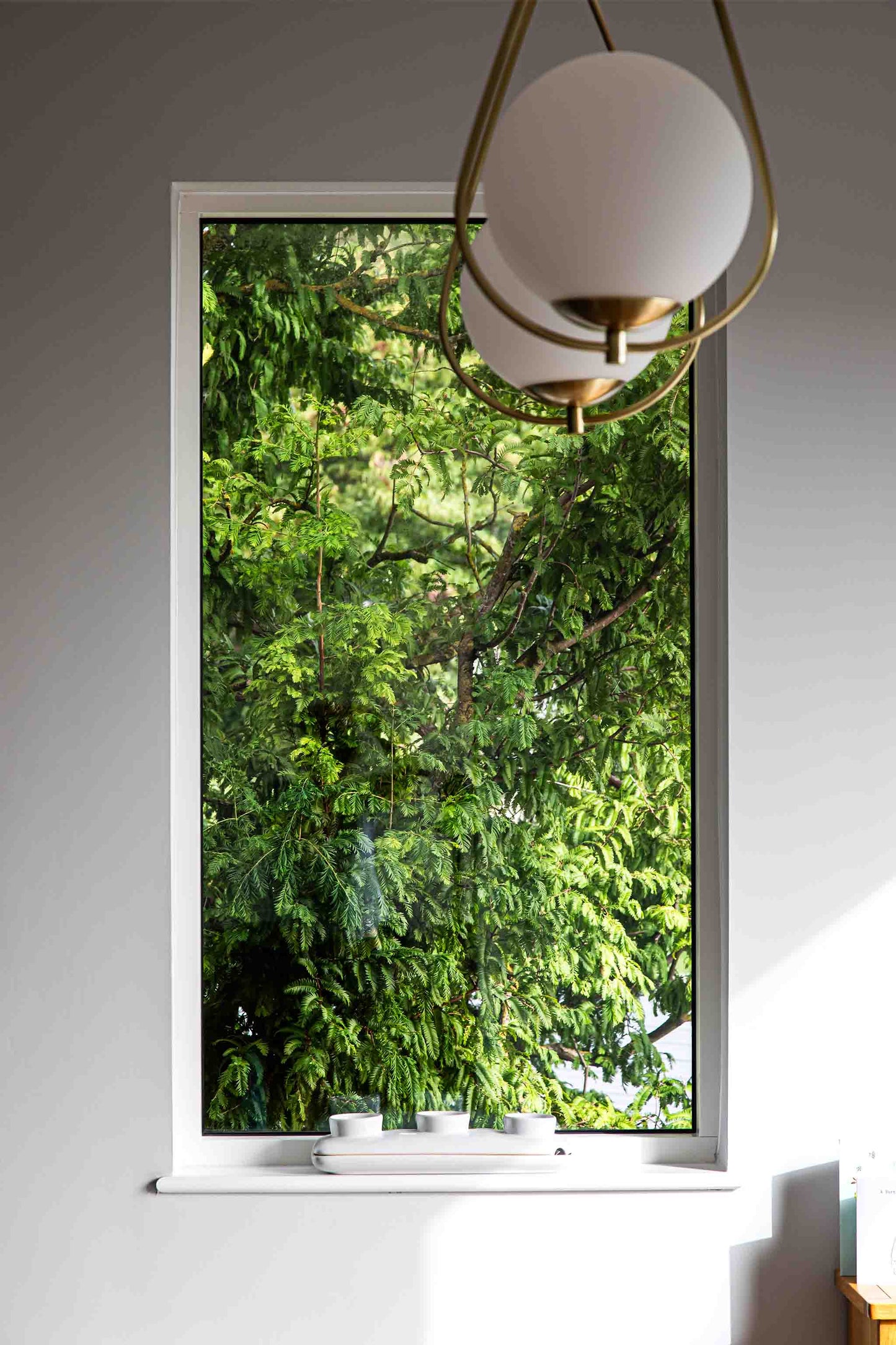 Triple-glazed window with a view of green trees, modern interior design.