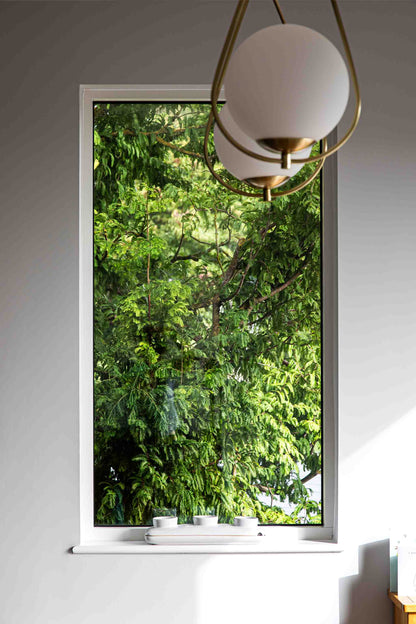 Triple-glazed window with a view of green trees, modern interior design.