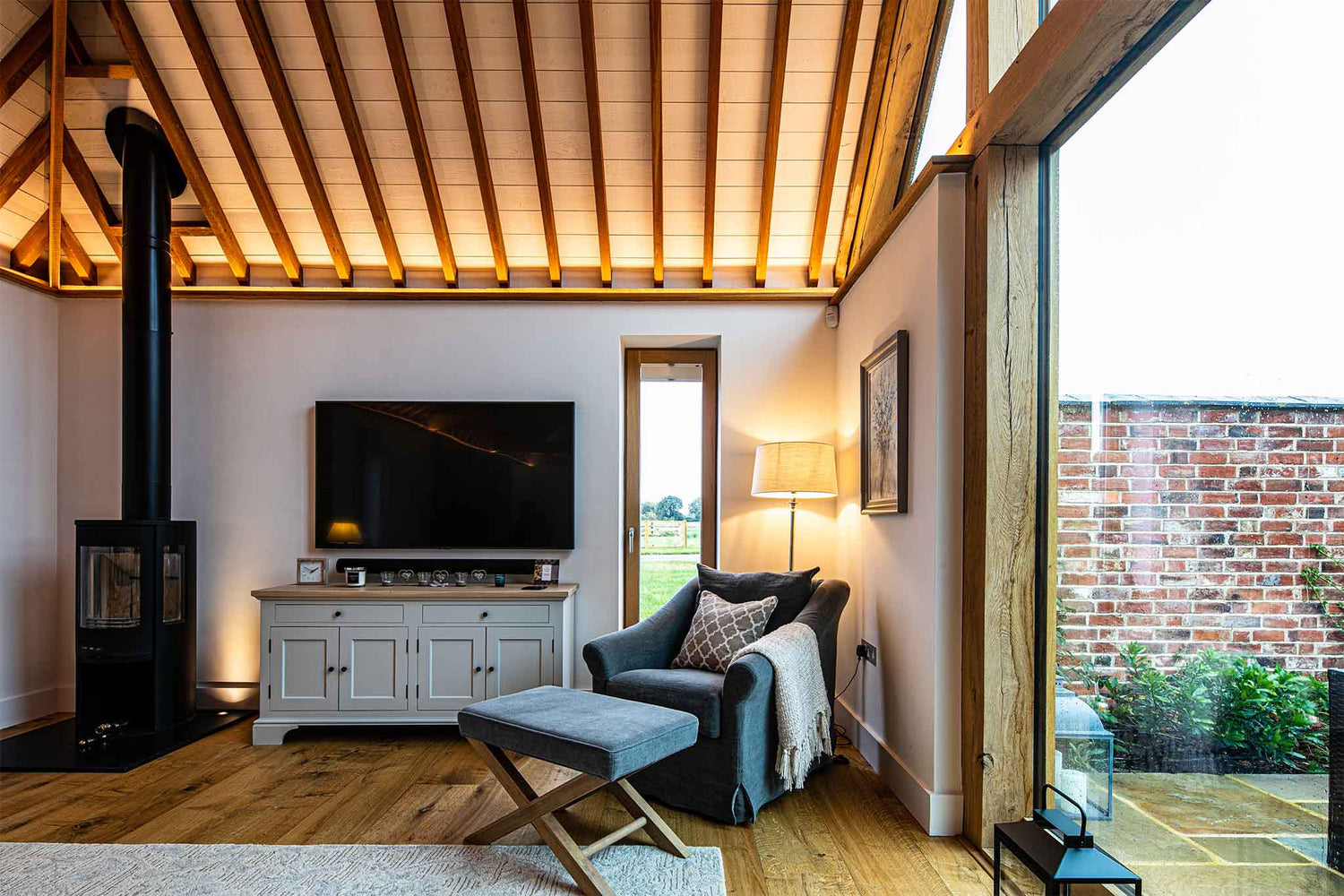 Modern living room with a television, fireplace, and large triple-glazed windows.