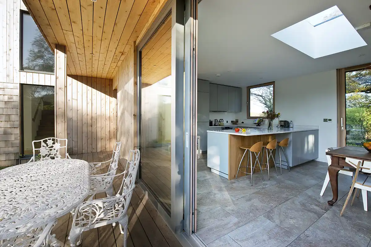 Image of an alu-clad timber sliding door in Mouse grey opening the kitchen onto the decking