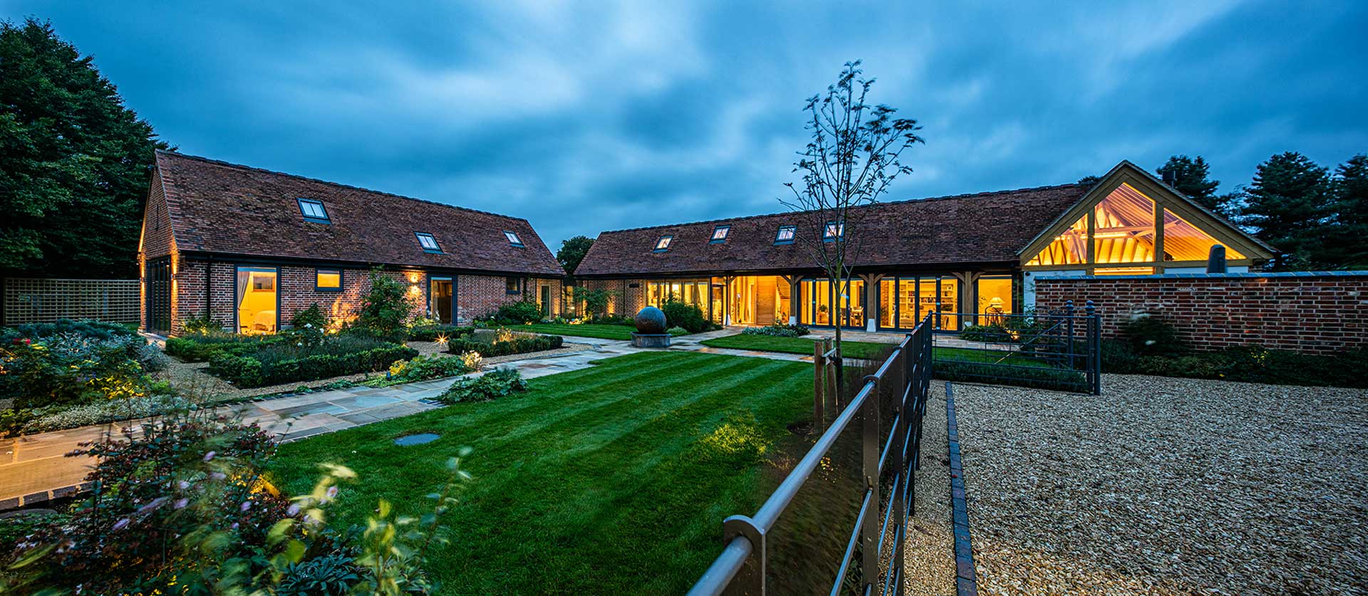 Image of two traditional barn buildings renovated to include a large gable window and triple glazed composite windows and doors