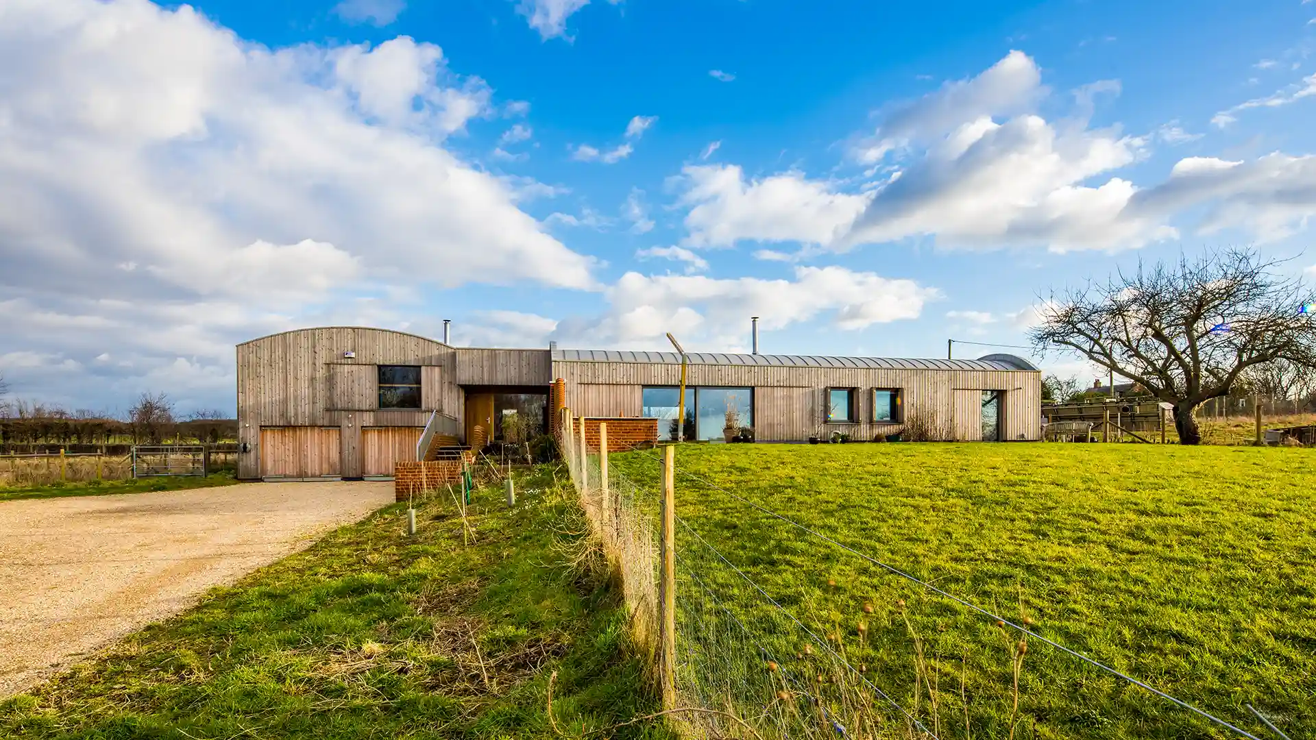 Image of a long, timber-clad, contemporary bunker-style home in a countryside setting